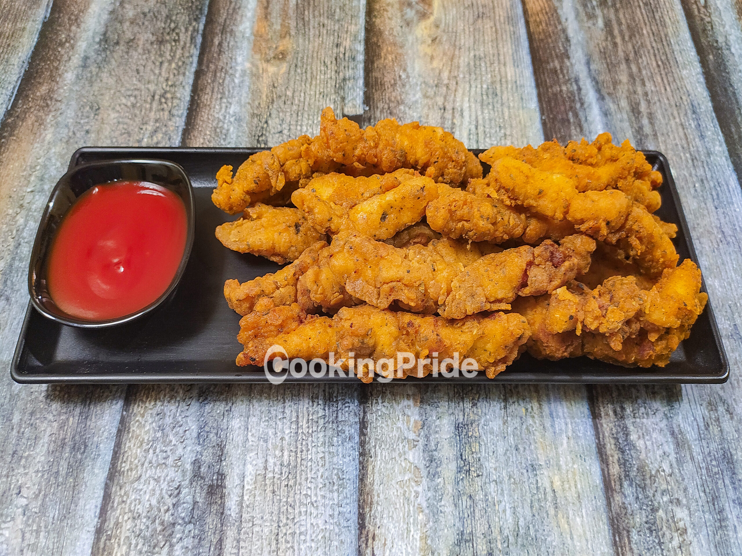 Crispy Chicken Strips by CookingPride Served in Black Plate with Tomato Sauce